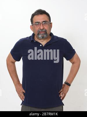 Un uomo indiano sorridente con un portiere in uno studio su sfondo bianco. Indossare occhiali e guardare la fotocamera. Foto Stock