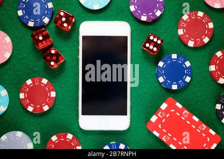 Chip per smartphone e casinò impilati su un feltro verde. Foto Stock