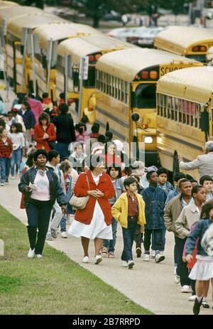 Gli studenti e gli insegnanti delle scuole elementari camminano dalla linea di autobus verso la costruzione della scuola. ©Bob Daemmrich Foto Stock