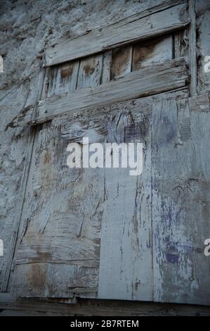 Vecchio porta di legno intemperato in cemento muro nella vecchia parte di Atene in Grecia simboleggiando i tempi difficili poveri economia e la vecchiaia Foto Stock