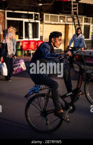 Iraq, Kurdistan iracheno, Arbil, Erbil. Un uomo sta rotolando su una ruota con la sua moto. Foto Stock
