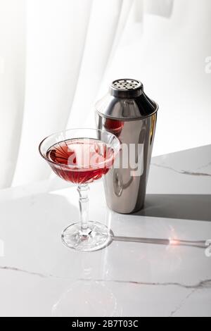 bicchiere di vino rosso vicino shaker su bianco Foto Stock