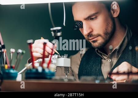 Fuoco selettivo del watchmaker che ripara il orologio da polso al tavolo Foto Stock