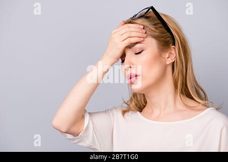 Donna triste con i capelli biondi che toccano la sua fronte a causa di avere mal di testa terribile Foto Stock