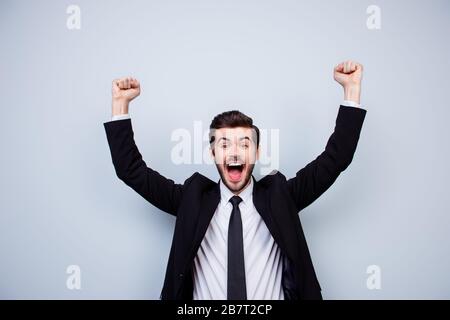 Felice uomo eccitato trionfando con pugni in rilievo su sfondo grigio Foto Stock