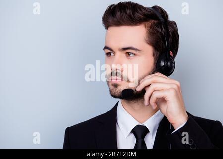 Primo piano ritratto di uomo concentrato in formalwear cercando di regolare il microfono delle sue cuffie Foto Stock