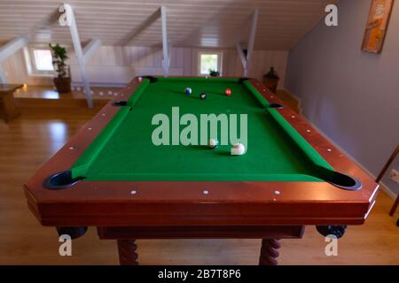 Tavolo da biliardo in legno con palle sparse in alto all'interno di un'accogliente sala loft Foto Stock