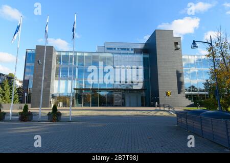 Ingresso di un moderno edificio della città di Naantali con tre pali della bandiera finlandese di fronte Foto Stock