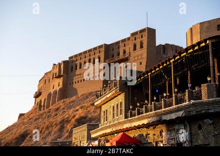 Iraq, Kurdistan iracheno, Arbil, Erbil. Vista da una caffetteria che si affaccia sulla strada al primo piano. Sullo sfondo è Erbil Qalat cittadella al tramonto. Foto Stock