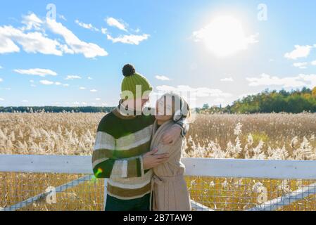 Felice giovane coppia multietnica che si abbraccia l'un l'altro contro la vista panoramica del campo di bullrush autunnale Foto Stock