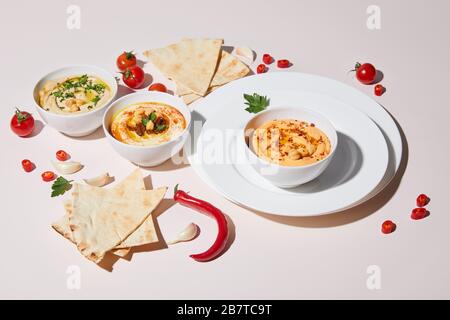 Piatti e ciotole con hummus, verdure fresche e pita pane su grigio Foto Stock