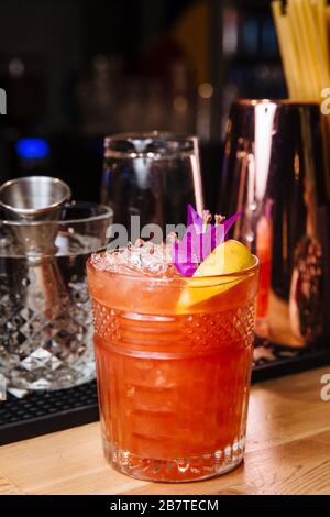 Pompelmo appena spremuto e succo d'arancia in un bicchiere, top decorato con una fetta di limone, fiori freschi e pezzi di ghiaccio. Foto Stock