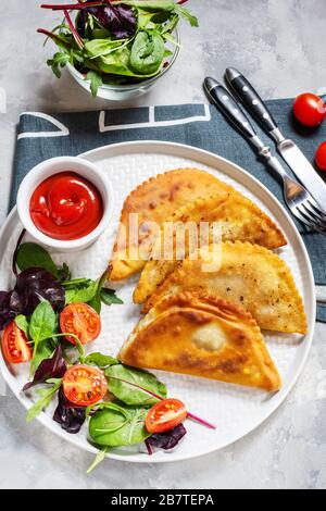 Cucina latinoamericana, messicana, cilena. Tradizionali empanadas di pasticceria cotta con carne di manzo su fondo in cemento. Vista dall'alto Foto Stock