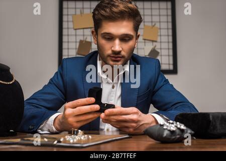 Fuoco selettivo di scatola di tenuta di appraiser di monili con anello vicino ai monili sulla tabella in officina Foto Stock