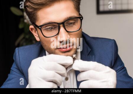 Fuoco selettivo di bel monili appraiser in guanti anello di tenuta con gemstone in officina Foto Stock