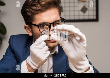 Gioielleria appraiser con lente di ingrandimento che esamina gemstone in officina Foto Stock