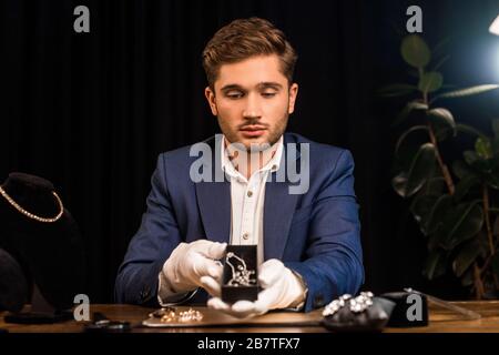 Bigiotteria appraiser scatola di tenuta con collana vicino gioielli sul tavolo in officina Foto Stock