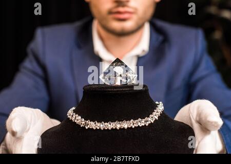 Vista tagliata di gioielli appraiser sostegno collana con collana e gemstone su sfondo nero Foto Stock