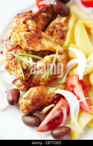 Ali di pollo arrosto con rosmarino fresco, patatine fritte e pomodori. Vista dall'alto. Foto Stock