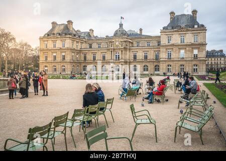 Paris France, 23 February 2020 : People resting on iconic green chairs at Jardin du Luxembourg gardens in front of the French Senate building in Paris Foto Stock