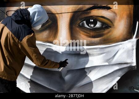 Atene, Grecia - 17 marzo 2020: Un giovane sta facendo un graffito ispirato alle misure contro il coronavirus (COVID-19) sulla terrazza di un blocco di Foto Stock