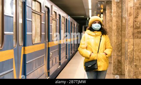 La giovane donna europea in maschera facciale monouso protettiva nella metropolitana. Nuovo coronavirus (COVID-19). Concetto di assistenza sanitaria durante un'epida Foto Stock