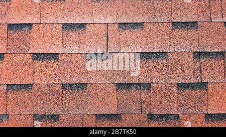 Vista ravvicinata su Asphalt Roofing Red Shingles background. Cerniere bituminose per tetti - costruzione di tetti, riparazione di tetti. Cerniere rosse sul tetto di Foto Stock