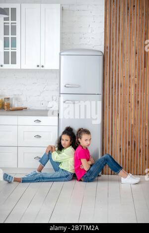 Due ragazze che siedono sul pavimento che si sentono turbate Foto Stock