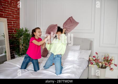 Due belle ragazze che combattono con i cuscini in camera da letto Foto Stock