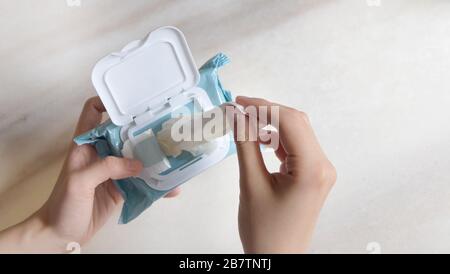 Mano che estrae un pezzo di tessuto umido da una confezione da viaggio di piccole dimensioni. Vista dall'alto. Foto Stock