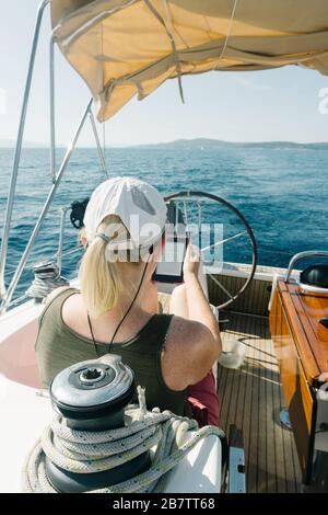 Donna seduta sul ponte di uno yacht godendo di lettura nel suo ebook. Concetto di viaggio e vacanza. Foto Stock