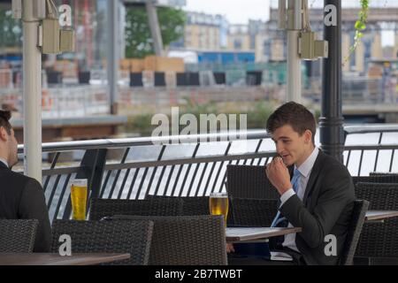 Due uomini d'affari chiacchierano e bevono birra al bar esterno. Canary Wharf, London Docklands, Regno Unito. Foto Stock