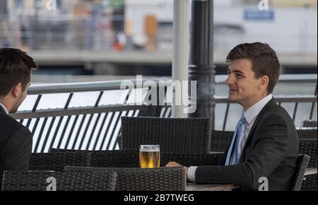 Due uomini d'affari chiacchierano e bevono birra al bar esterno. Canary Wharf, London Docklands, Regno Unito. Foto Stock