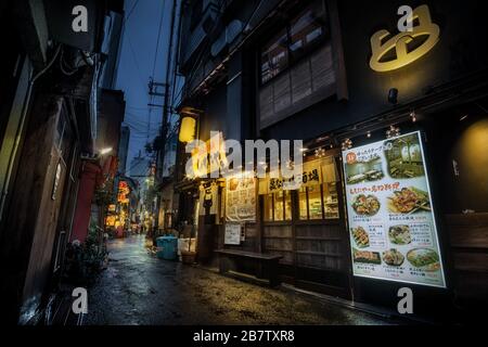 Vista di un ristorante in un vicolo stretto in una serata piovosa ad Osaka, Giappone. Foto Stock