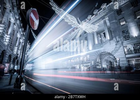 Immagine notturna a lunga esposizione del traffico che passa davanti alle luci di Natale a Regent Street, Londra. Foto Stock