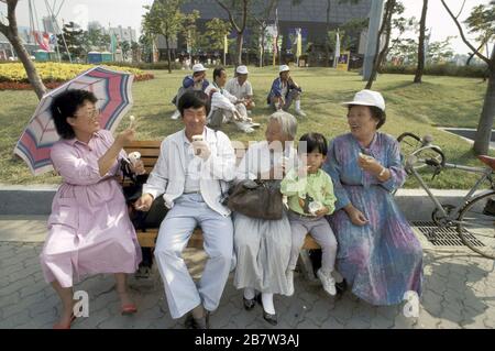 Seul, Corea del Sud, 1988: Famiglia che mangia gelato al di fuori della sede olimpica durante i Giochi estivi. 1998 ©Bob Daemmrich Foto Stock