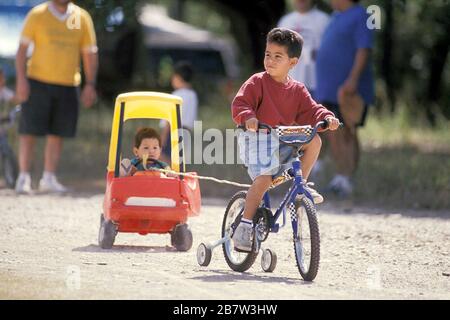 Austin, Texas: Il ragazzo ispanico tira il fratello con la bicicletta. ©Bob Daemmrich Foto Stock