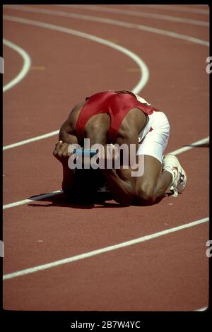 Seoul Corea, 1988: Esausto relè runner scende in ginocchio dopo aver attraversato il traguardo della gara durante la gara in pista alle Olimpiadi estive. ©Bob Daemmrich Foto Stock