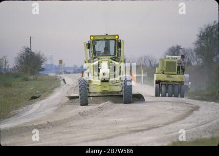 Texas: Servizi del governo della contea: I lavoratori della contea utilizzano attrezzature pesanti per effettuare riparazioni stradali su un'autostrada rurale della contea. ©Bob Daemmrich Foto Stock