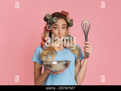 Casalinga con frusta e ciotola che soffia le labbra Foto Stock