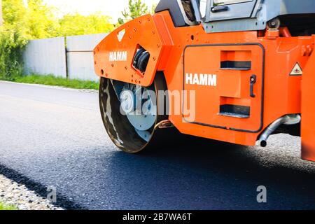 Lavoratori e macchine asfaltatrici. Rullo pesante in movimento sulla carreggiata. Costruzione di una nuova strada a Targoviste, Romania, 2020 Foto Stock