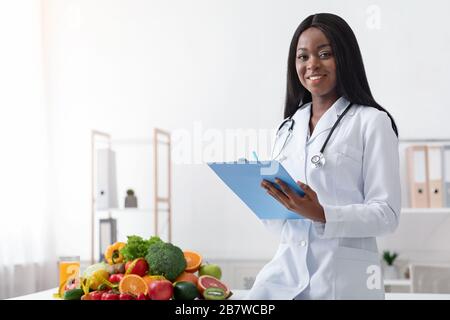 Positivo dietologo nero femmina in possesso di carta medica Foto Stock