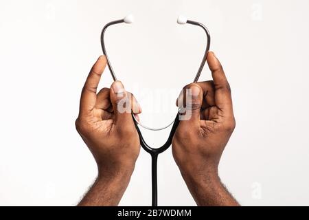 Mani di un medico che indossa lo stetoscopio prima del controllo Foto Stock
