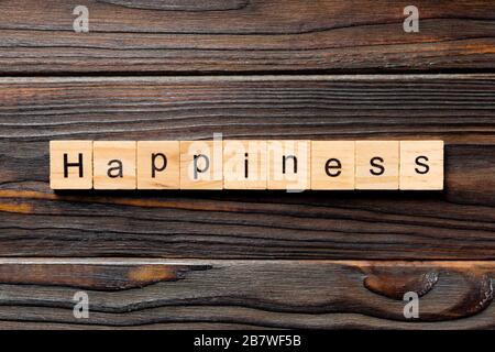 Parola di felicità scritta su blocco di legno. Testo di felicità sul tavolo di legno per il vostro desing, concetto di vista dall'alto. Foto Stock