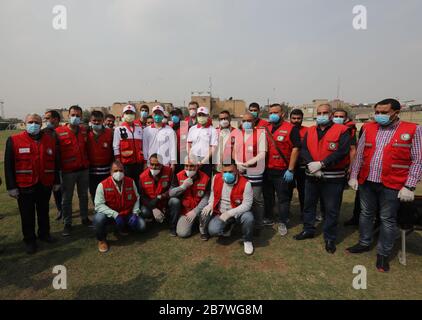 Baghdad, Iraq. 18 Marzo 2020. I membri della Società della Mezzaluna Rossa irachena posano per una foto di gruppo con esperti cinesi presso un centro comunitario a Baghdad, Iraq, il 16 marzo 2020. Un team cinese di sette esperti sanitari sta fornendo indicazioni e assistenza medica per contenere l'epidemia di COVID-19 in Iraq. Gli esperti stanno aiutando le autorità sanitarie irachene a dare priorità alle strategie di risposta, colmare le lacune nei test e portare l'esperienza cinese a beneficio del paese lacerato. Il team di esperti cinesi è arrivato a Baghdad il 7 marzo e si prevede che rimarrà nel paese per un mese. Credit: Xinhua/Alamy Live News Foto Stock