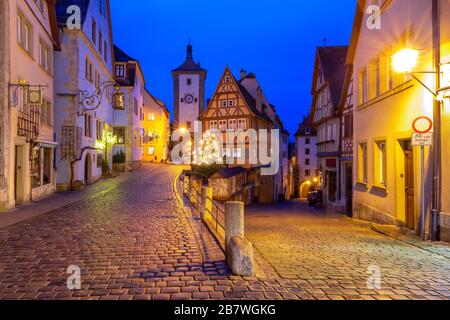 Arredato ed illuminato il Natale street con porta e torre Plonlein nella vecchia città medievale di Rothenburg ob der Tauber, Baviera, Germania meridionale Foto Stock