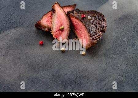 bistecca alla griglia con pepe colorato su un tabellone di ardesia avvolto in fumo. Manzo come uno stile di vita principale basso carb. Foto Stock