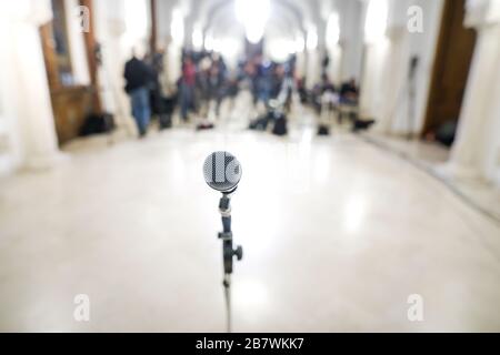 Immagine con profondità di campo bassa (messa a fuoco selettiva) con un microfono davanti alle telecamere durante una conferenza stampa. Foto Stock