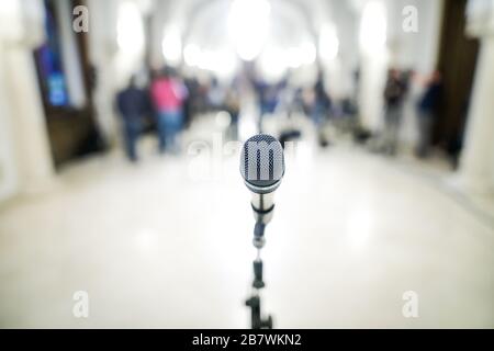 Immagine con profondità di campo bassa (messa a fuoco selettiva) con un microfono davanti alle telecamere durante una conferenza stampa. Foto Stock