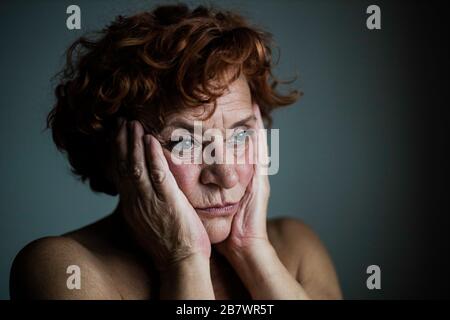 Donna matura per la finestra pensando alla vita Foto Stock